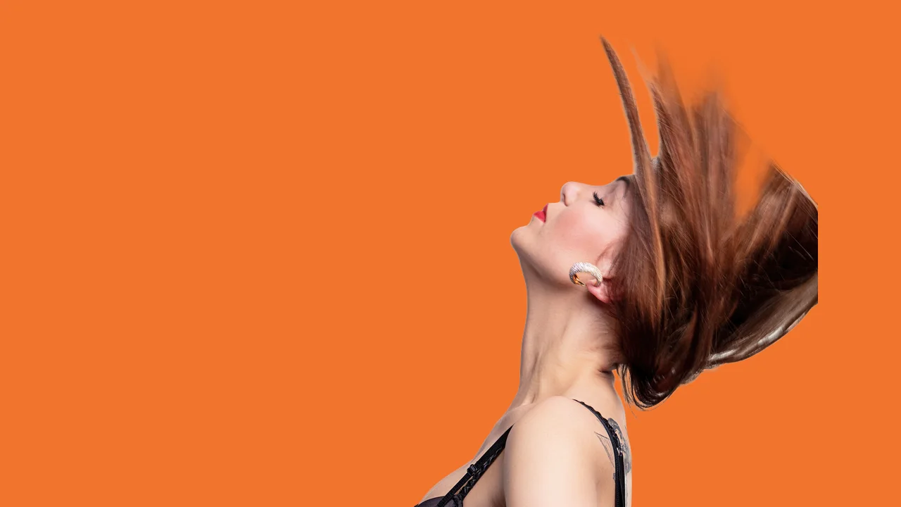 A 1280 by 720 thumbnail: the woman with flying hair cut out and placed on the right of a bright orange background